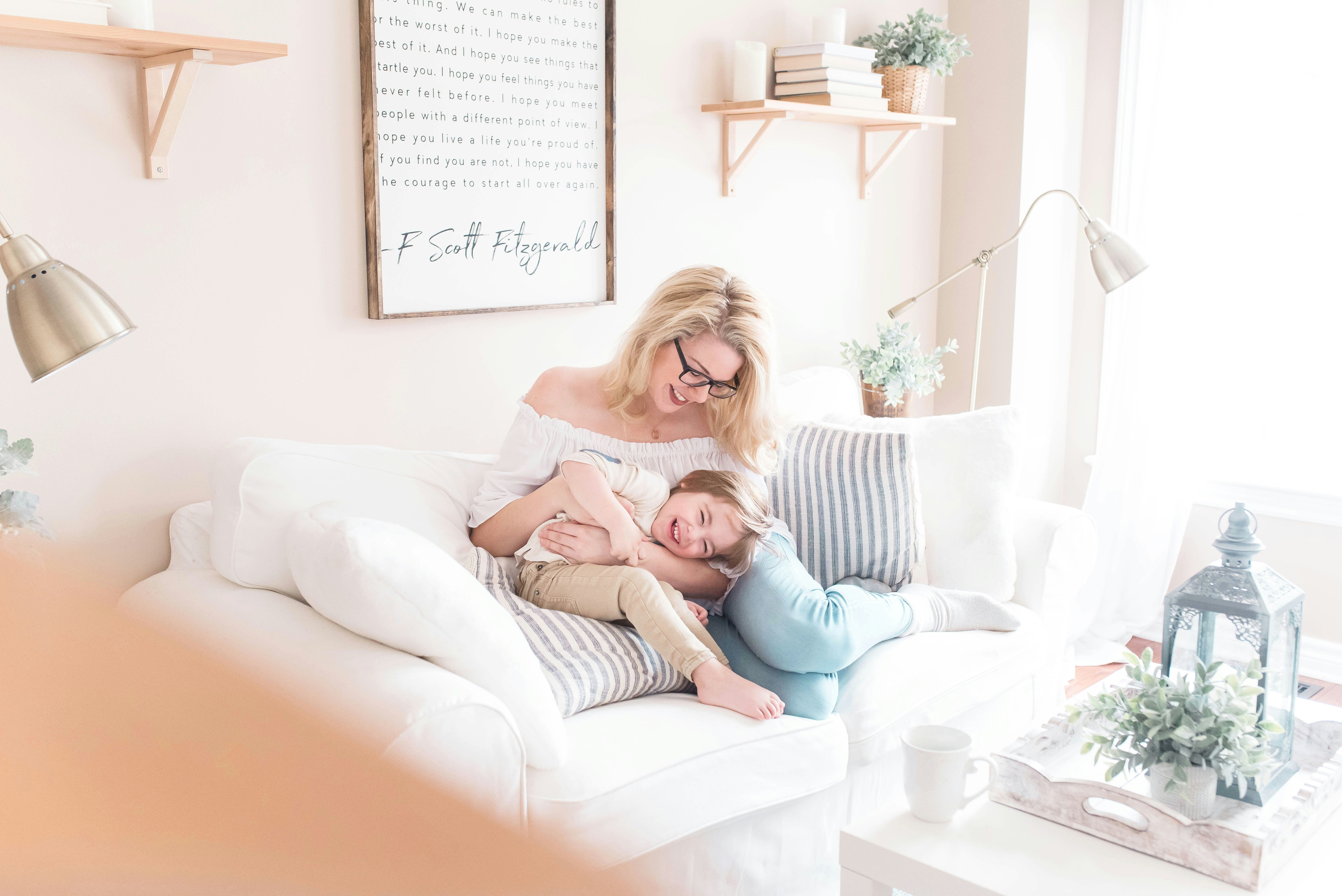 A parent and child laughing together on the couch at home